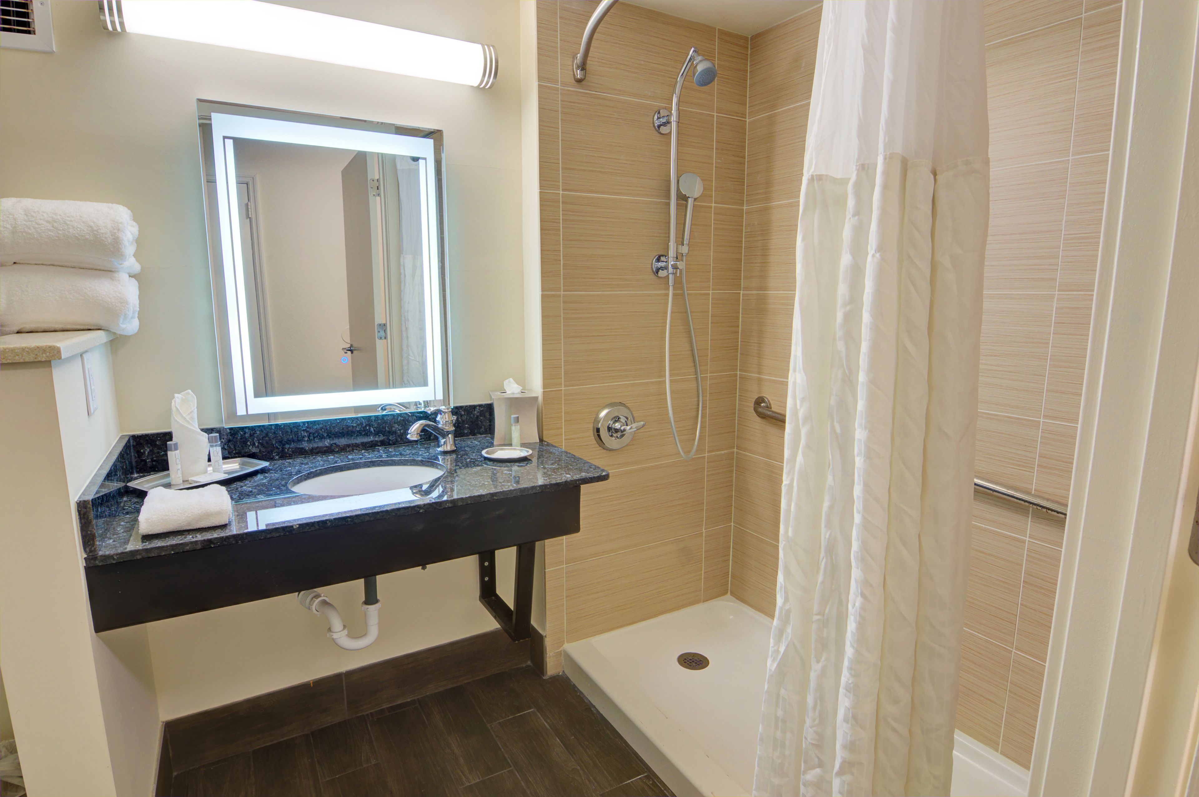 A bathroom with a sink, mirror, and shower.