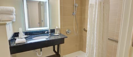 A bathroom with a sink, mirror, and shower.