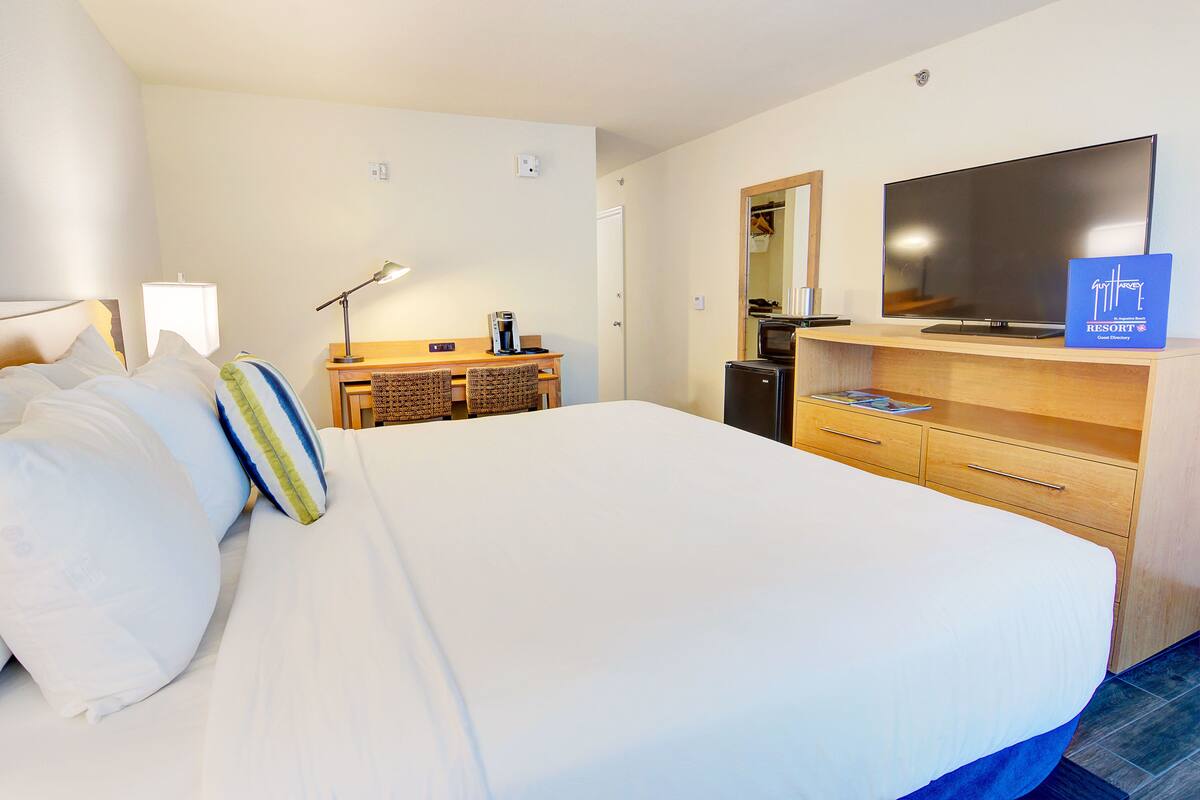 Een hotelkamer met een groot bed, een bureau met een computer, een flatscreen televisie en een koffiezetapparaat.