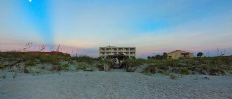 A beachfront hotel with a central building and a smaller structure nearby.