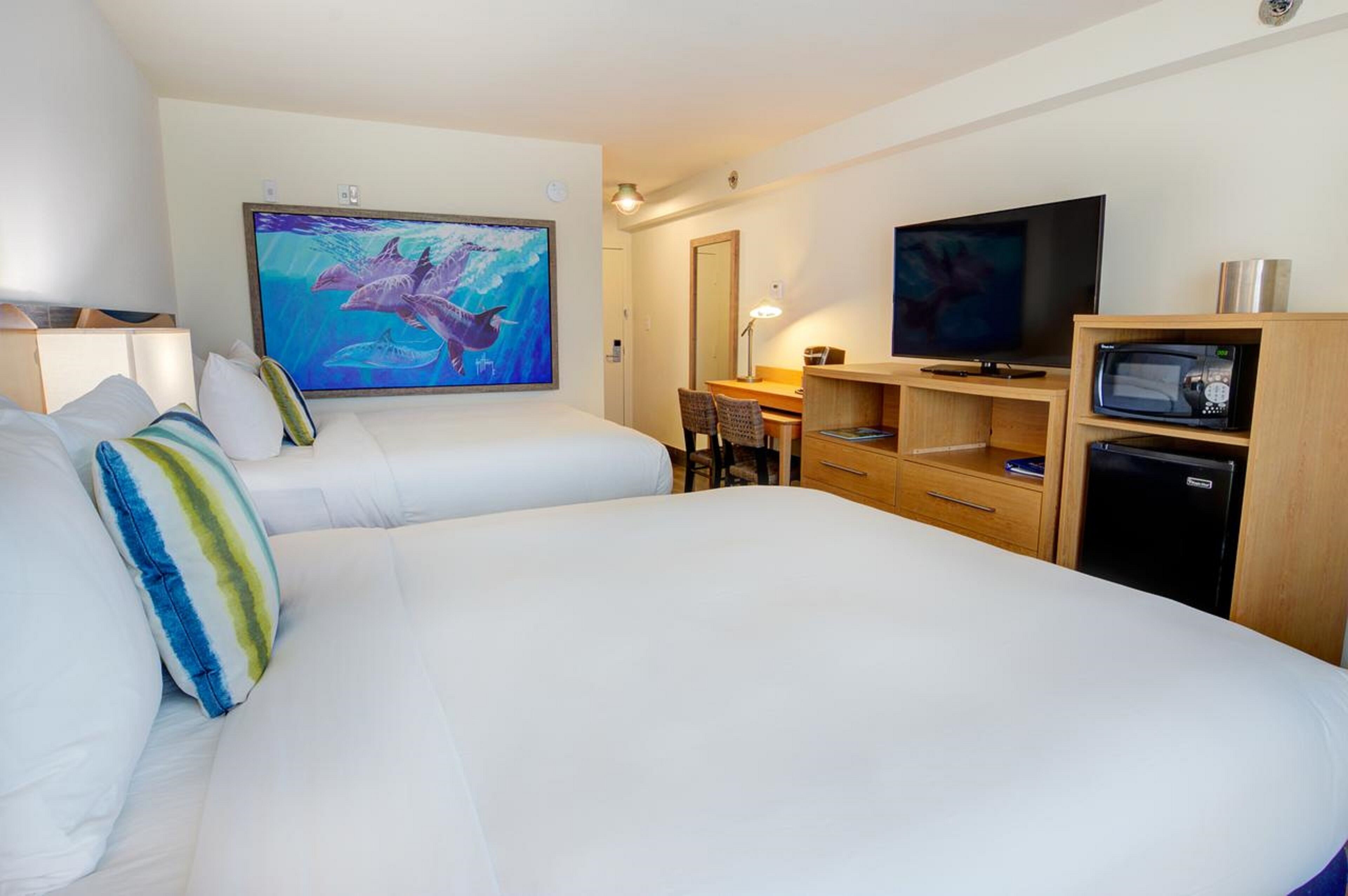 Una habitación de hotel con dos camas, un escritorio, un televisor y un microondas.