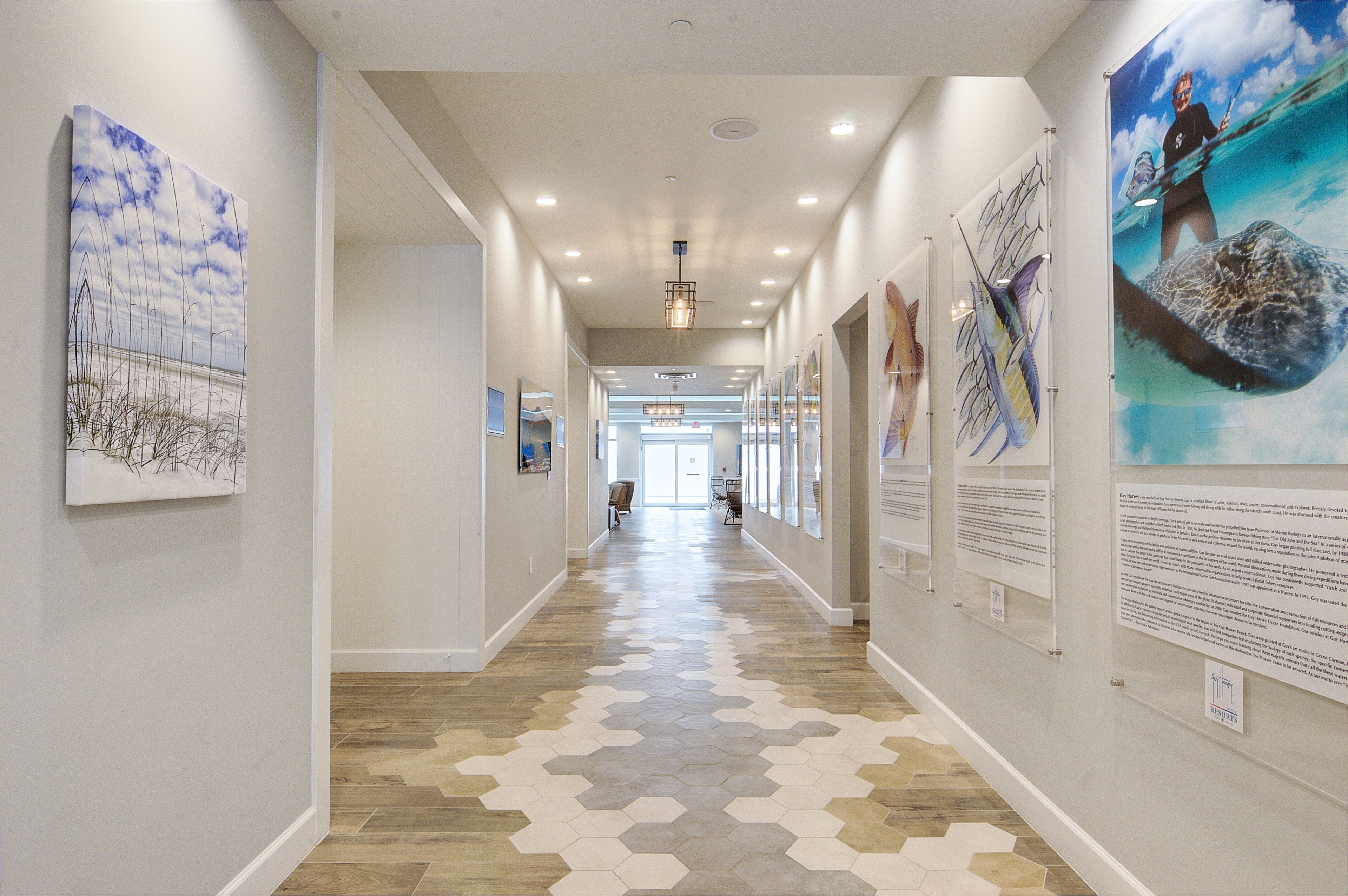 A hallway with hexagonal patterned flooring, wall-mounted artwork, and informational plaques.