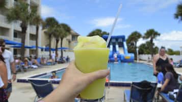 Guests can enjoy a refreshing drink by the pool, surrounded by lounge chairs and umbrellas.
