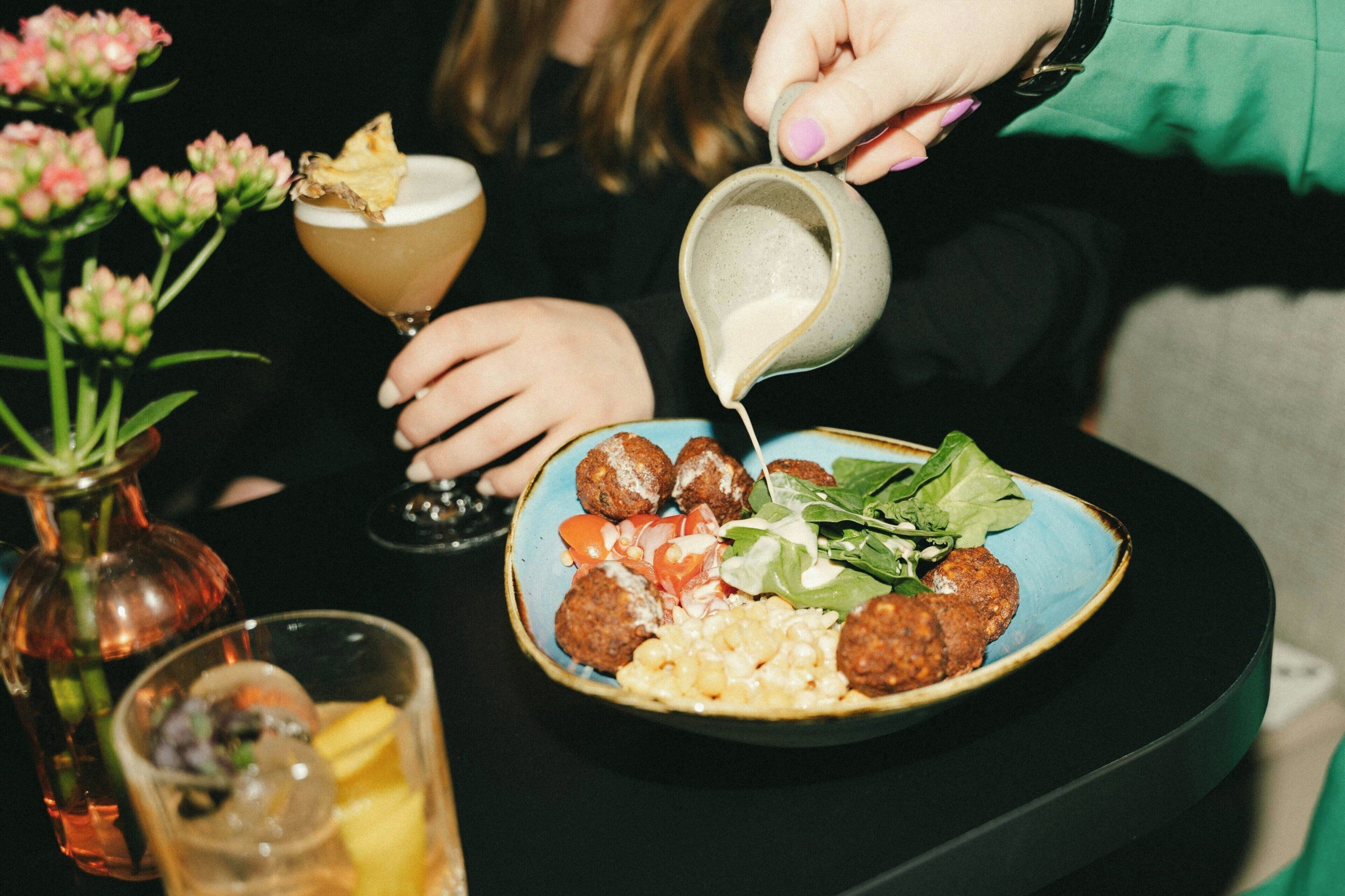 A table with a plate of food, a drink, and a pitcher.