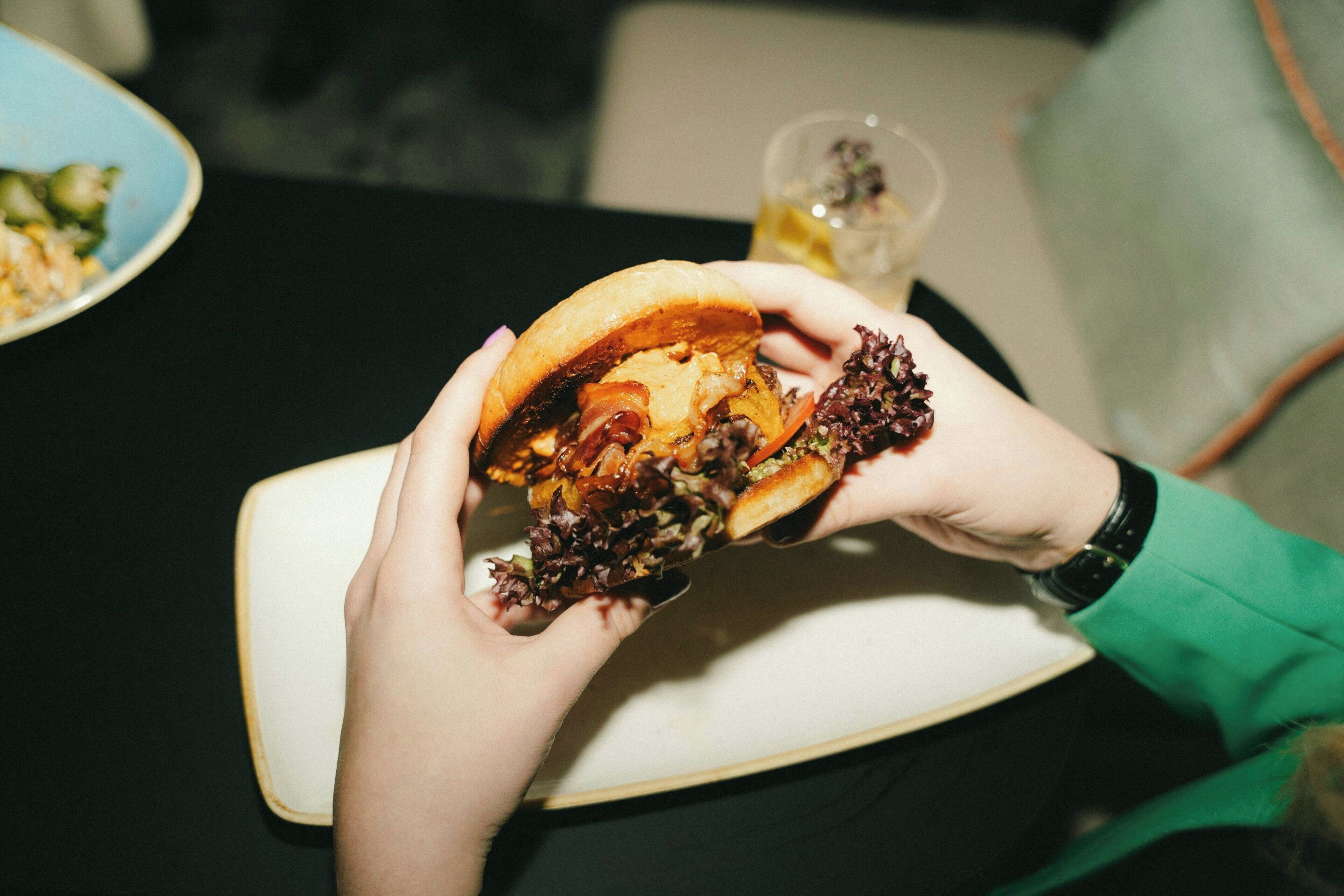 A person holding a sandwich with visible ingredients.