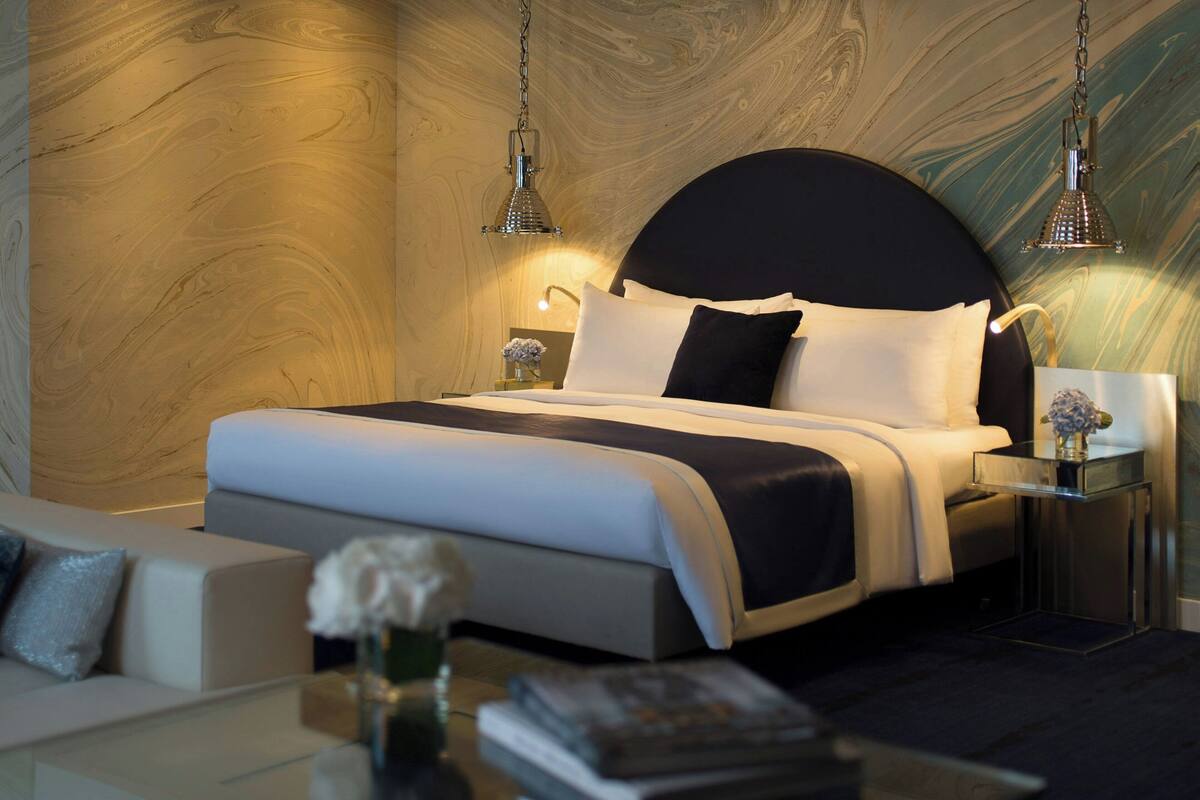 Une chambre moderne avec un grand lit, des tables de chevet, un canapé et une table basse en verre.