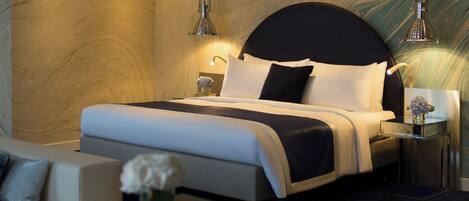 A modern bedroom with a large bed, bedside tables, a sofa, and a glass coffee table.