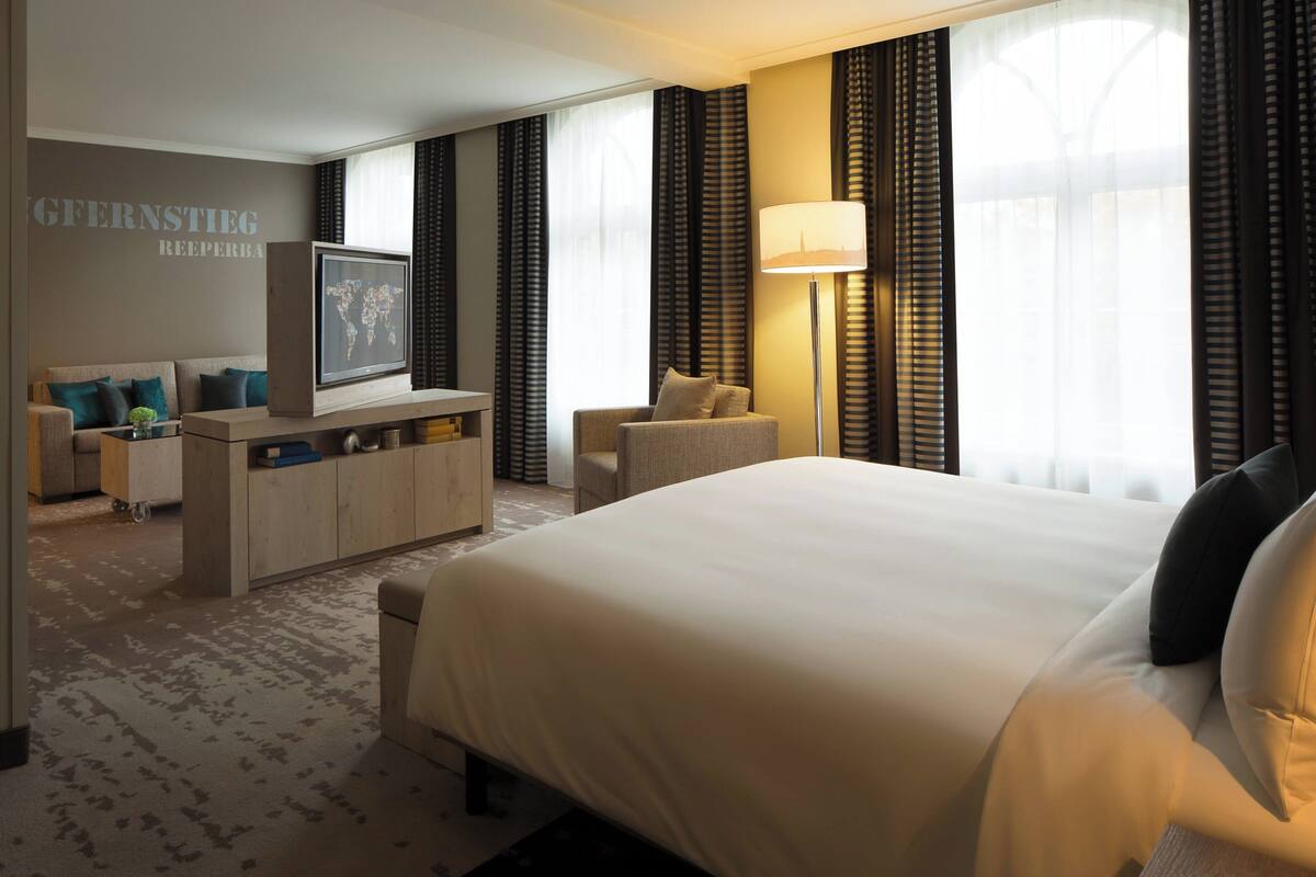 Une chambre d’hôtel avec un grand lit, un bureau doté d’un téléviseur à écran plat, un canapé et une lampe.