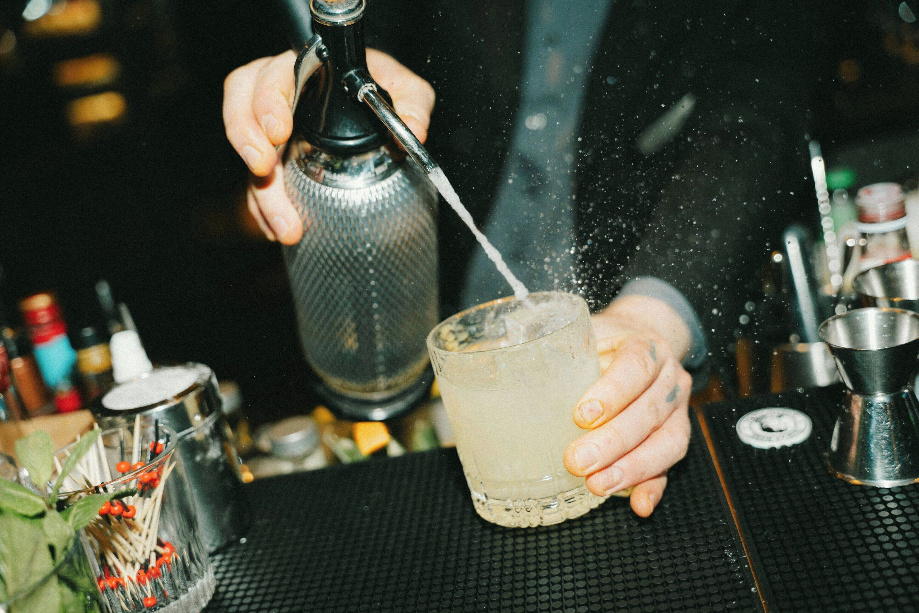 A person pouring a drink from a shaker into a glass.