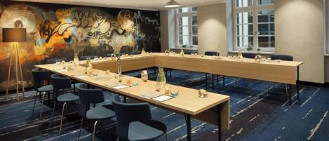 A conference room with a long table, chairs, and a mural on the wall.