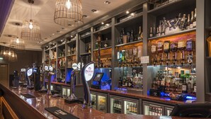 A bar area with multiple taps, shelves of liquor bottles, and a well-lit ceiling. - Stradey Park Hotel (Llanelli)