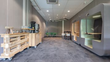 Una sala de conferencias moderna con un escritorio de madera, sillas, una estación de café y una mesa verde.