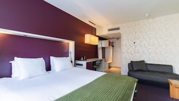 Una habitación de hotel con cama, escritorio, sofá y un diseño de pared con motivos.