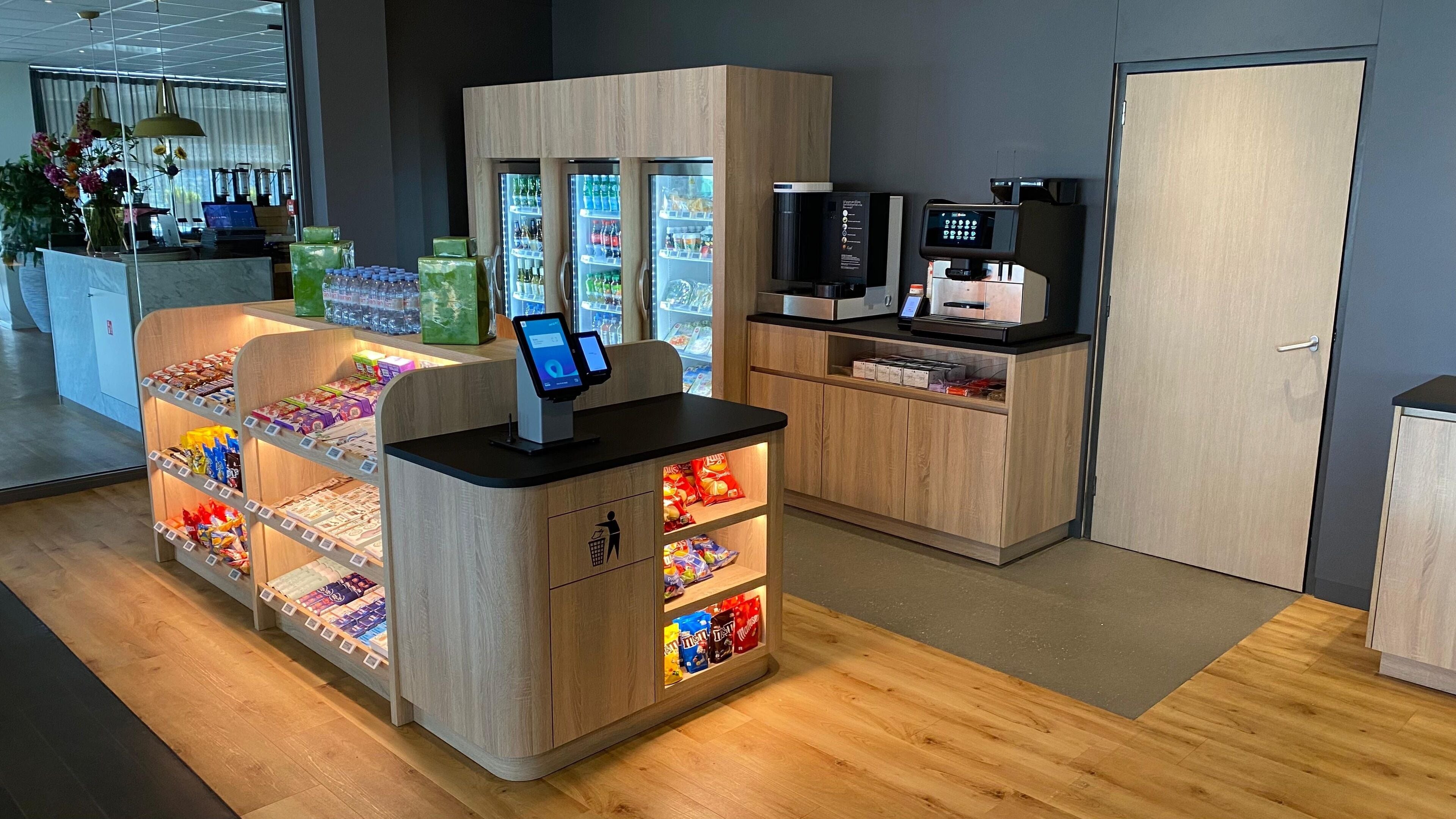 A self-service kiosk with a digital screen, snacks, and a beverage cooler.