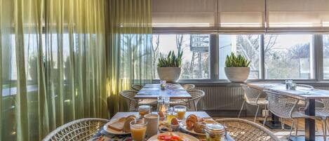 A breakfast setting with a table set for two, featuring croissants, eggs, and fruit.