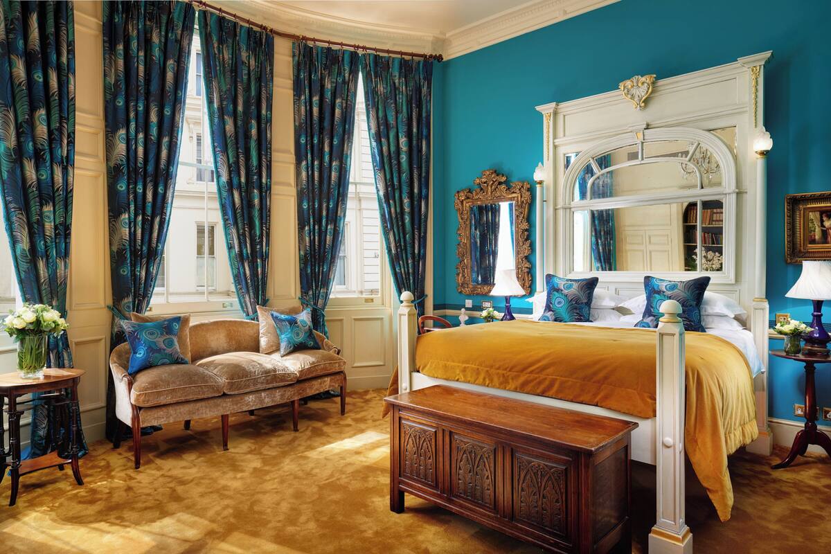 A bedroom with a large bed, a nightstand, a dresser, and a window with curtains.