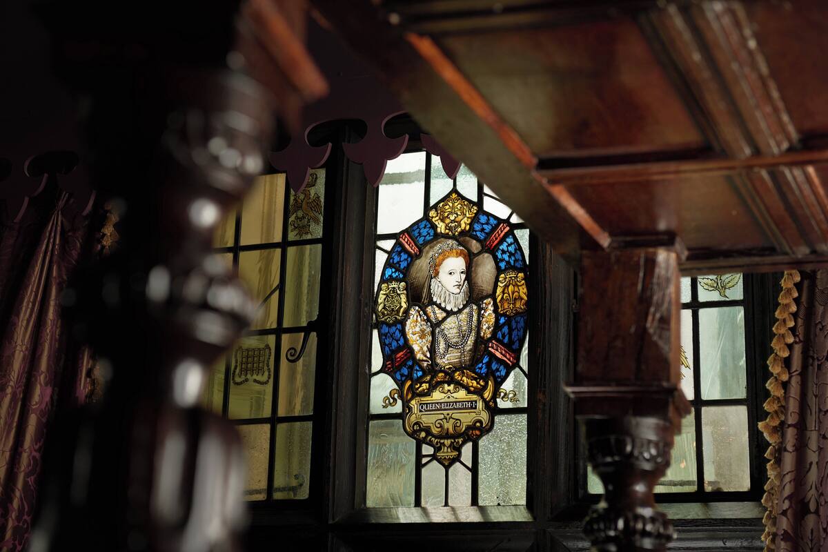 A stained glass window with a heraldic design and the name "Queen Elizabeth I".