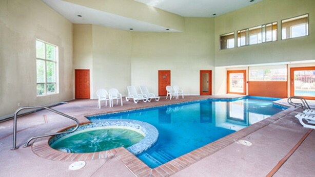 Piscina interior con hidromasaje, sillas de descanso y vistas al exterior.