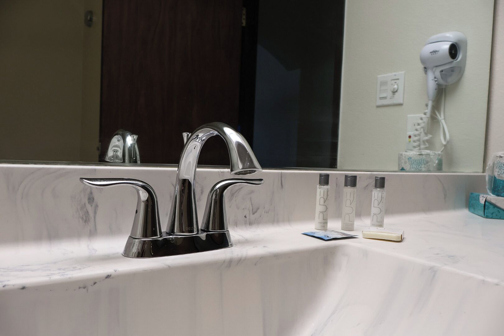 Un baño con un lavamanos moderno, un espejo y un secador de pelo en la pared.