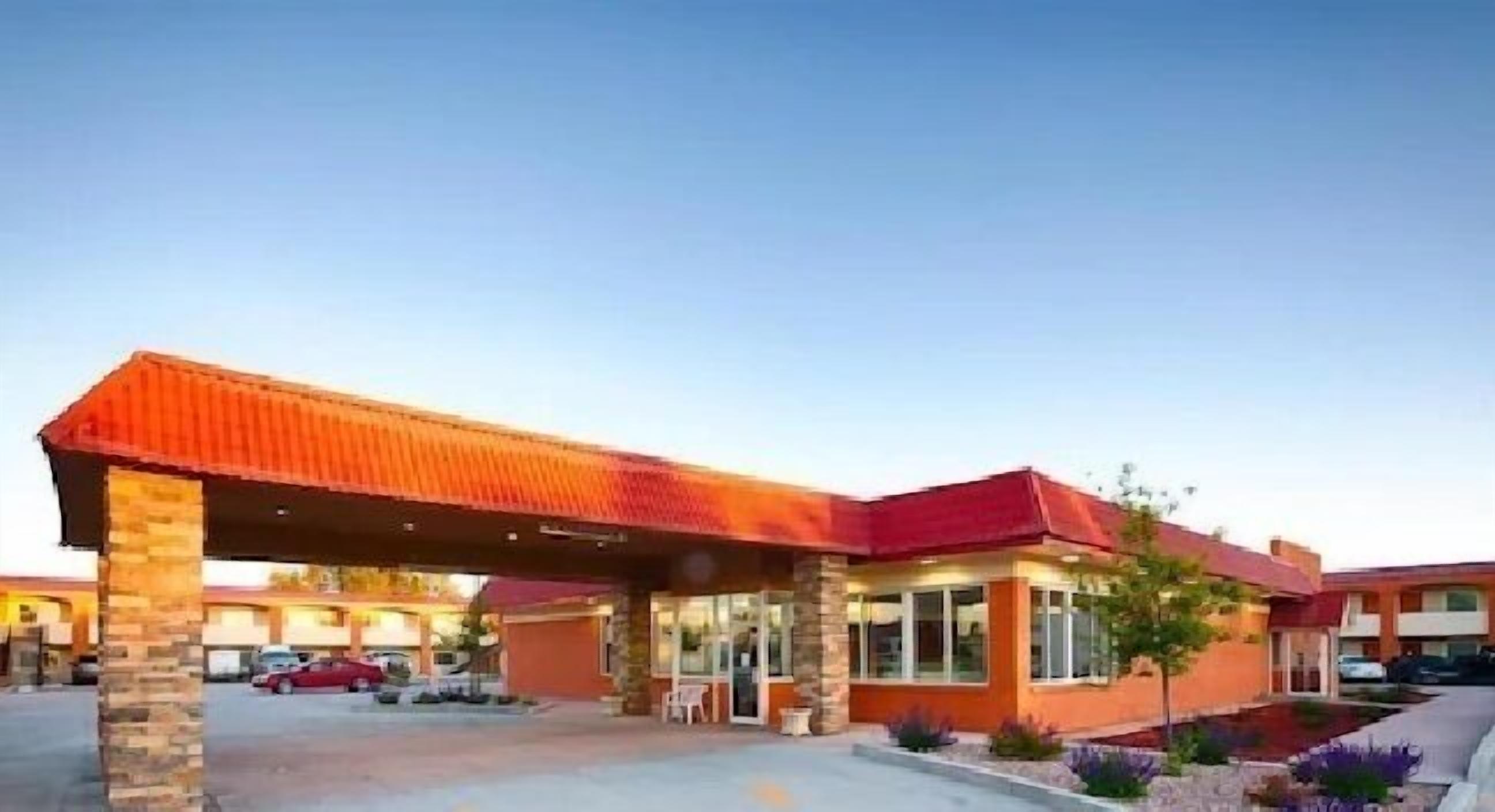 A hotel with a covered entrance, a parking lot, and a landscaped garden area.