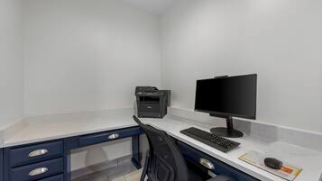 Un espacio de oficina moderno con un escritorio, silla, monitor de computadora, teclado e impresora.