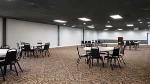 A conference room with multiple tables and chairs, carpeted floor, and a whiteboard on the wall.