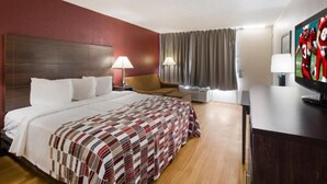 A hotel room with a large bed, two bedside tables with lamps, a TV on a wooden cabinet, and a window with curtains.