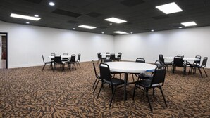 A conference room with a patterned carpet, white walls, and black chairs around a central table.