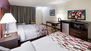 A hotel room with two beds, a desk, a television, and a microwave.