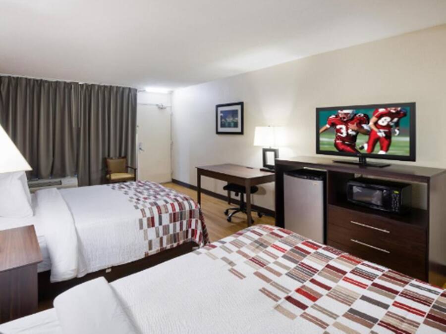 A hotel room with two beds, a desk, a television, and a microwave.