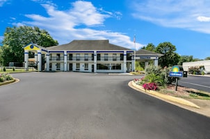 A Days Inn with a central parking lot, a covered entrance, and a sign indicating nearby amenities.