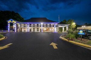 A hotel with a central entrance, a covered waiting area, and a parking lot.