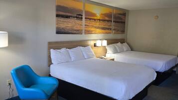 Una habitación de hotel con dos camas, una silla azul y una pared con pinturas de atardecer.