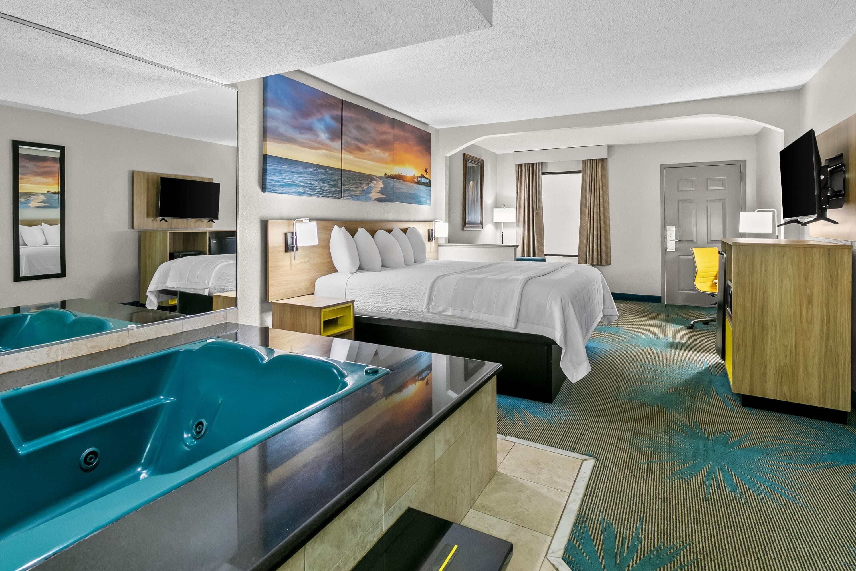 Una habitación de hotel con una cama grande, una bañera, un escritorio y una televisión.