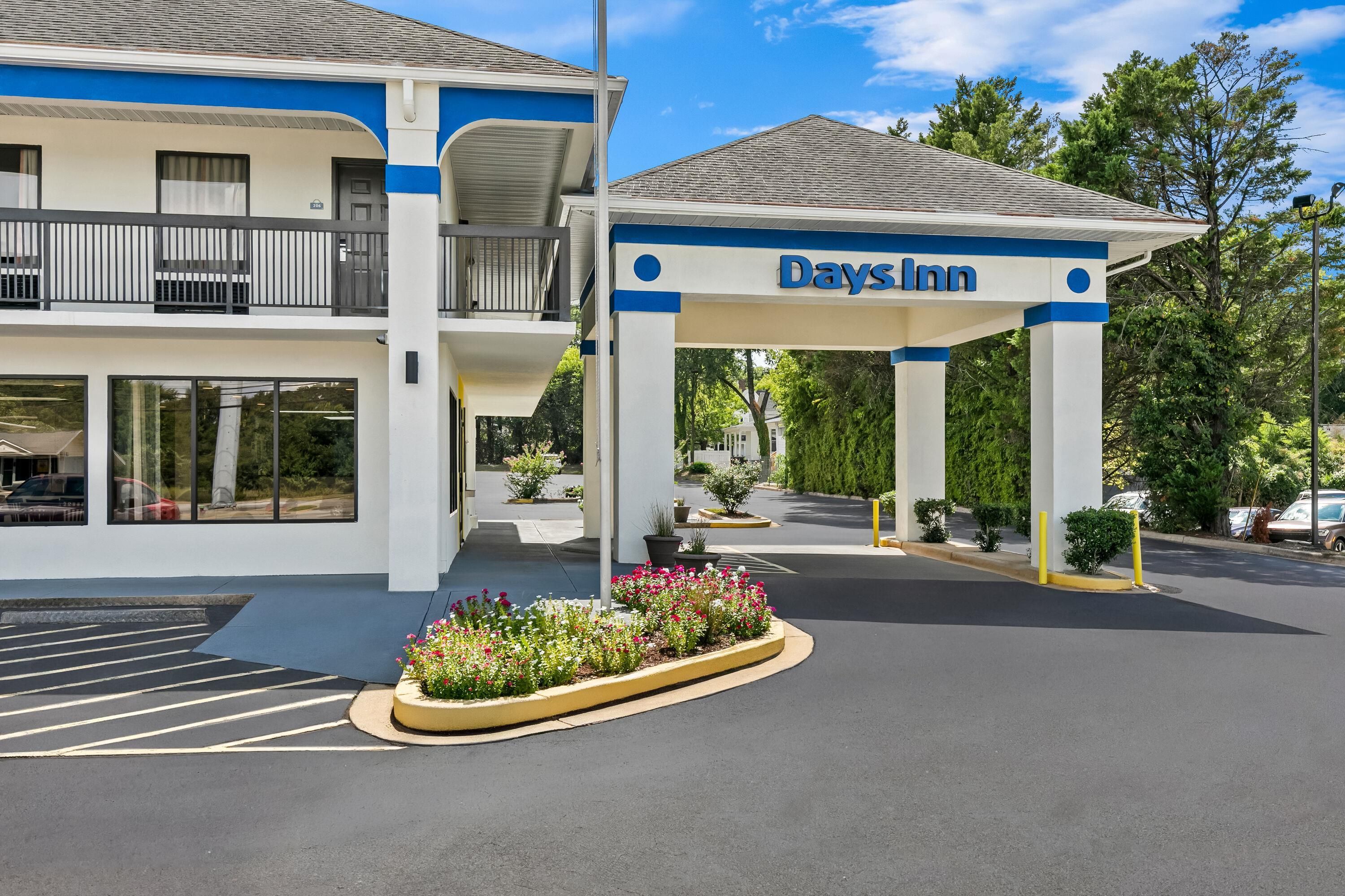 A Days Inn building with a covered entrance, a parking lot, and a flower bed.