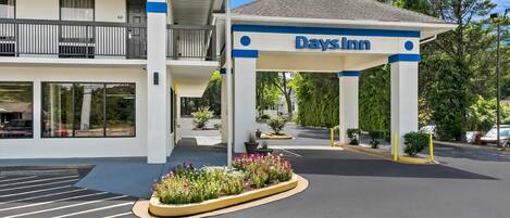 A Days Inn building with a covered entrance, a parking lot, and a flower bed.