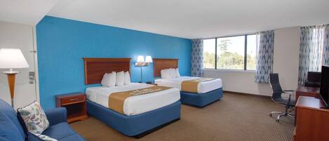 A hotel room with two beds, a desk, and a couch.