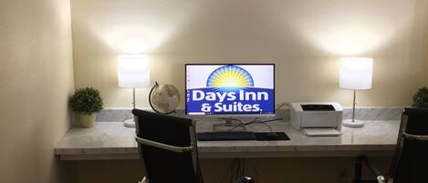 Ein Hotelrezeptionsschalter mit einem Computermonitor, der das Days Inn Logo zeigt, zwei Lampen, einem Globus und einer kleinen Pflanze.