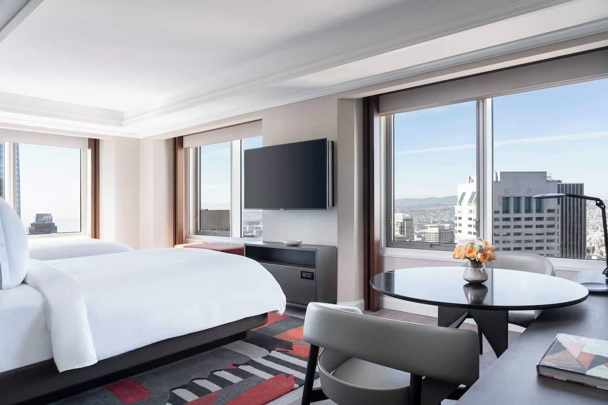 Una habitación de hotel moderna con una cama grande, un escritorio con silla, una mesa de comedor y un televisor.