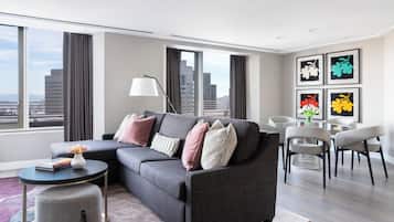 A modern living room with a grey sectional sofa, a round coffee table, a side table, and a dining area with chairs.