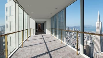 A high-rise building corridor with large windows offering a city view, including a prominent tower.