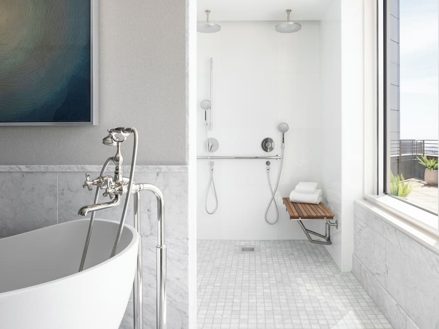 A modern bathroom with a freestanding bathtub, a shower with a glass enclosure, and a small wooden bench.