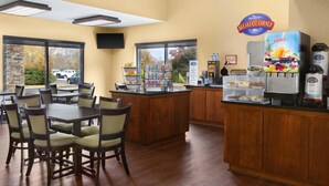 A breakfast area with a counter, seating, and a juice dispenser. - Baymont by Wyndham Rocky Mount (Rocky Mount)