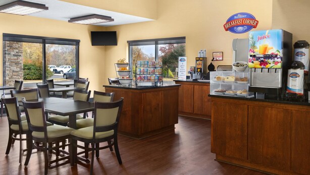 A breakfast area with a counter, seating, and a juice dispenser.