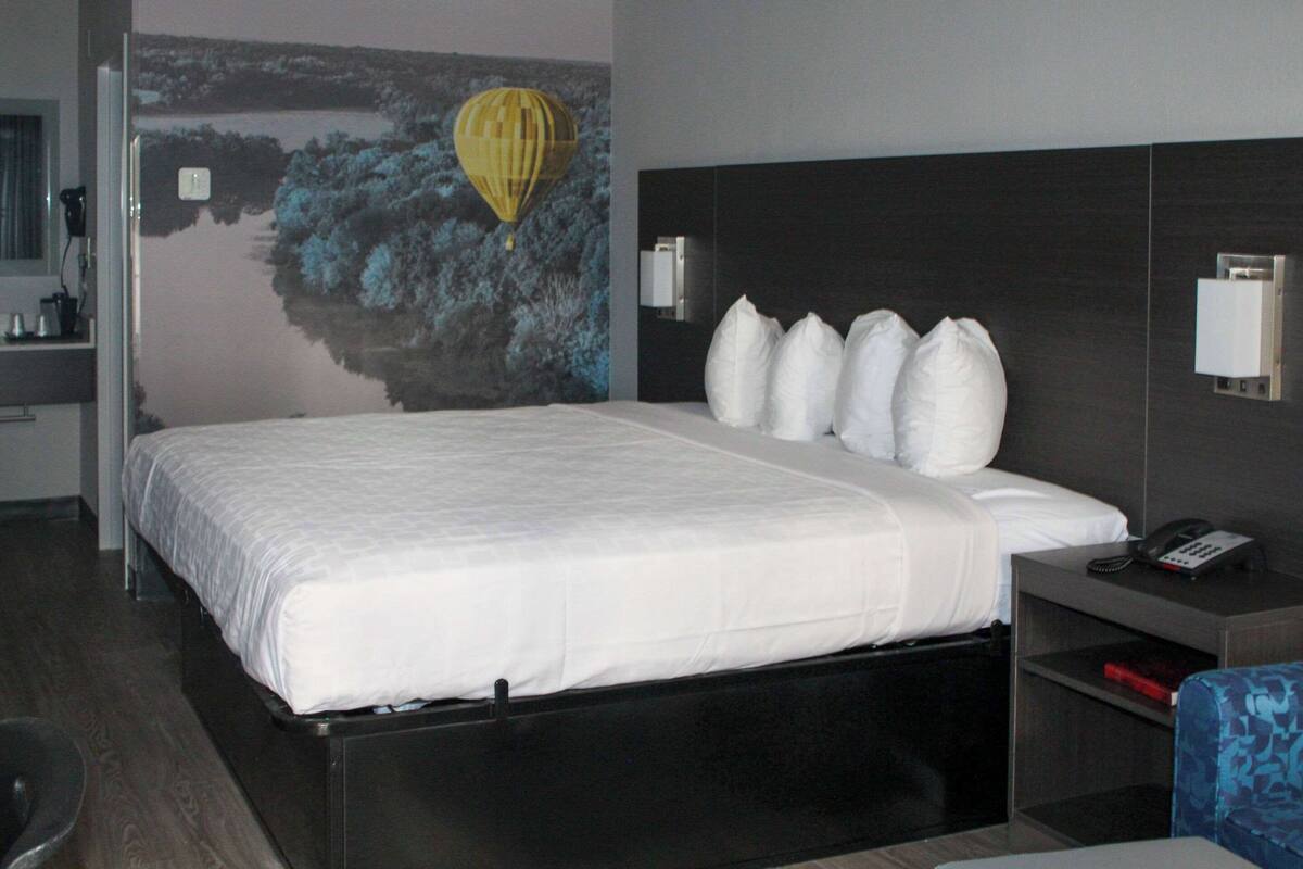 Ein Hotelzimmer mit einem großen Bett, einem Nachttisch mit Telefon und einer Wandleuchte.