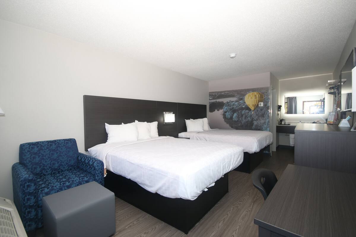 Ein Hotelzimmer mit zwei Betten, einem Schreibtisch, einem Stuhl und einer kleinen Couch.