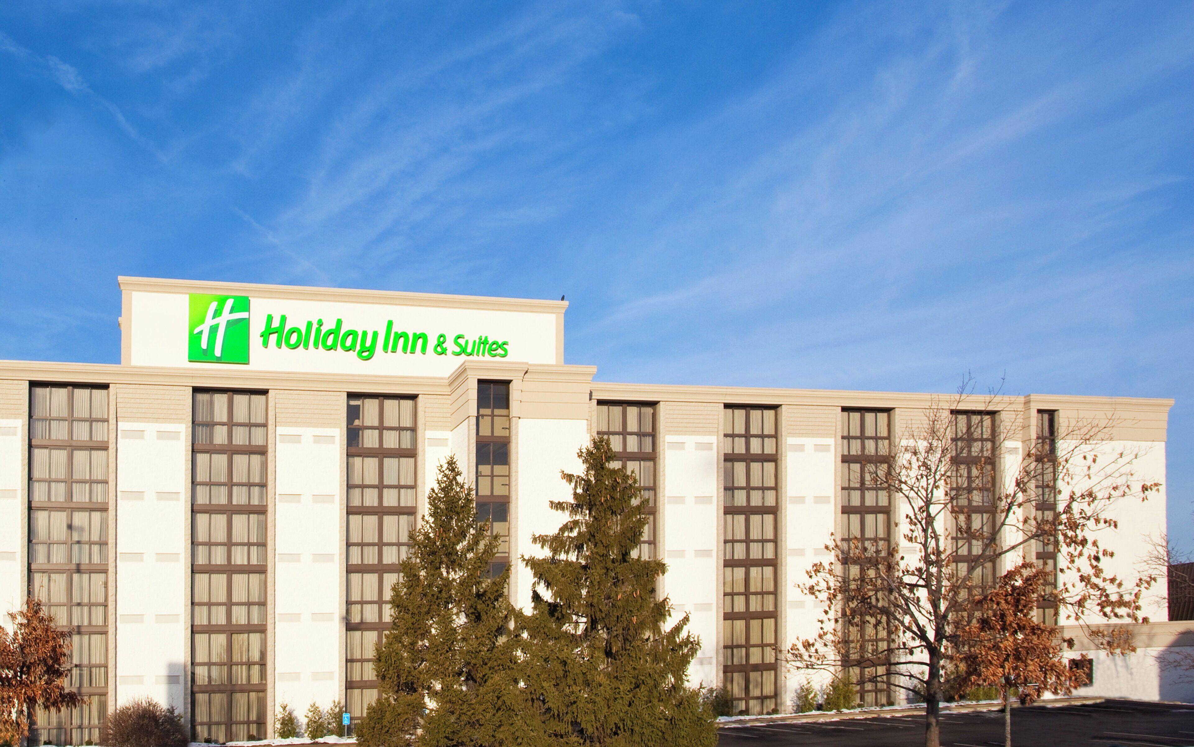 A Holiday Inn & Suites building with a clear sky.