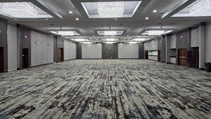 A large, empty conference room with a patterned carpet, recessed lighting, and skylights. - Holiday Inn Hotel & Suites Cincinnati - Eastgate by IHG (Cincinnati)