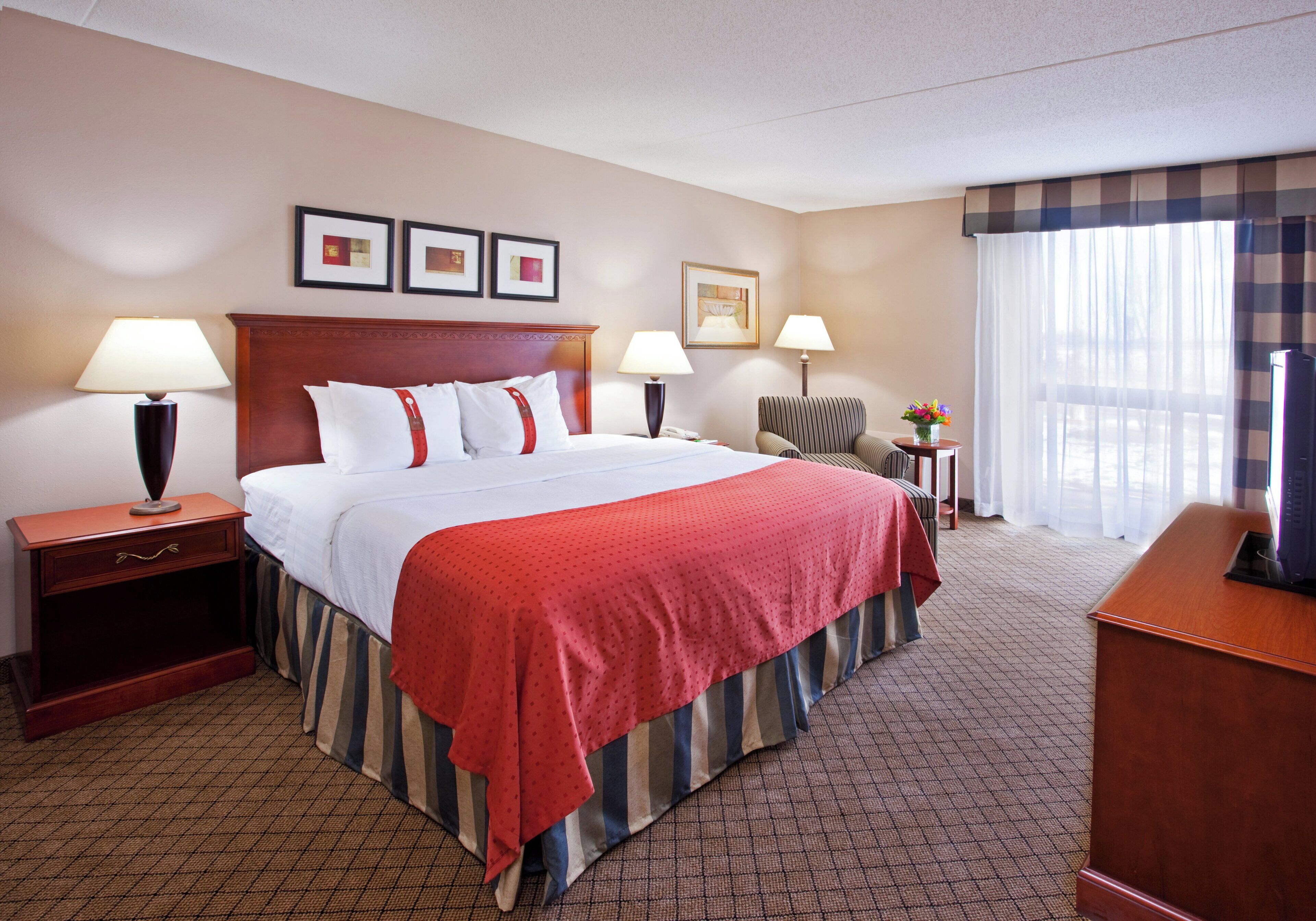 A hotel room with a large bed, two bedside tables with lamps, a desk, and a chair.