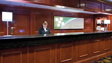A reception desk with a sign for Holiday Inn, wooden paneling, and a carpeted floor.